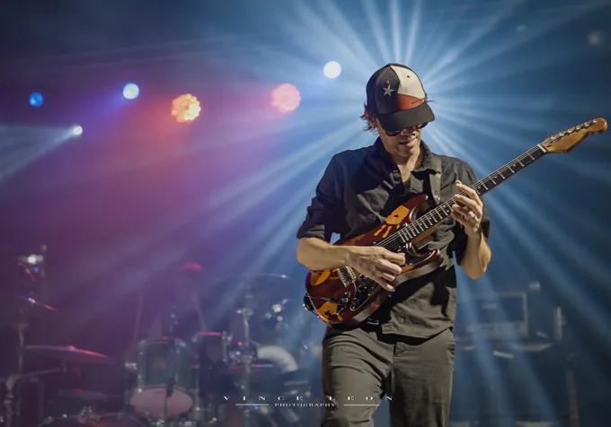 Guitarist performing beneath blue and red lights