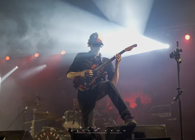 Guitarist in front of bright white stage beams