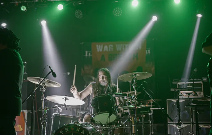 Drummer performing under green lights